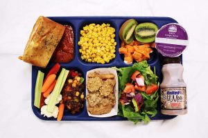school lunch tray filled with fruits, vegetables, chicken and milk