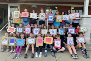 Group of students holding artwork.