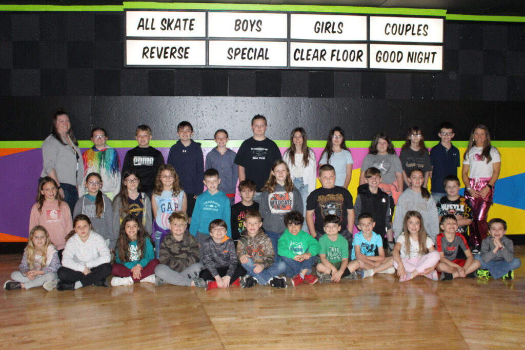 Group picture of students standing on the roller rink floor.