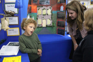 From left: Center McMichen kindergarten student Wayne Anthony tells MCS Superintendent Dr. Shelby Haines and another student about his literature fair project.